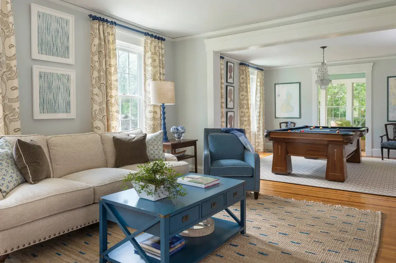 Przytulny salon w stylu kolonialnym z wygodną kanapą, fotelem i stołem bilardowym.