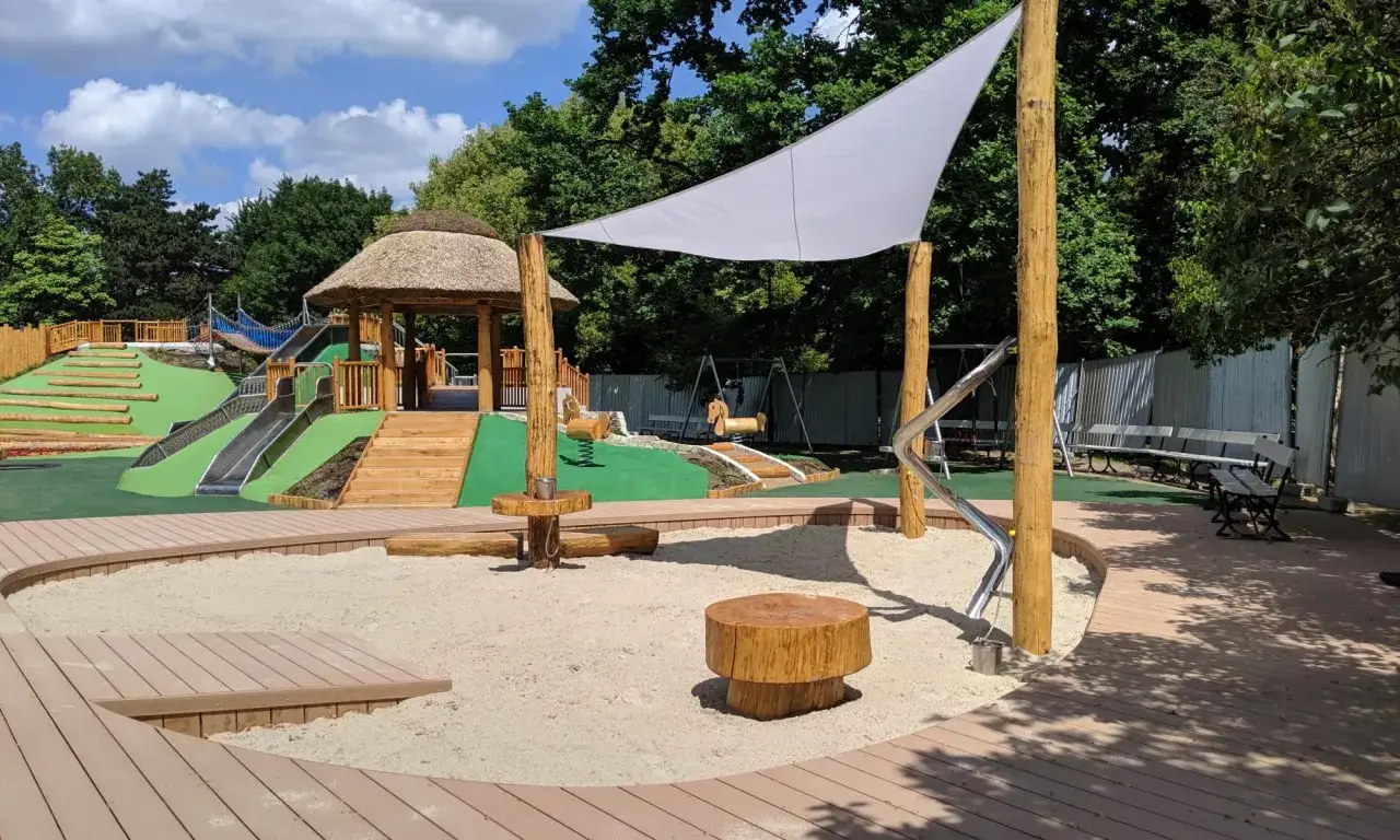 Nowoczesny plac zabaw w Parku Ujazdowskim z piaskownicą, zjeżdżalniami i huśtawkami.