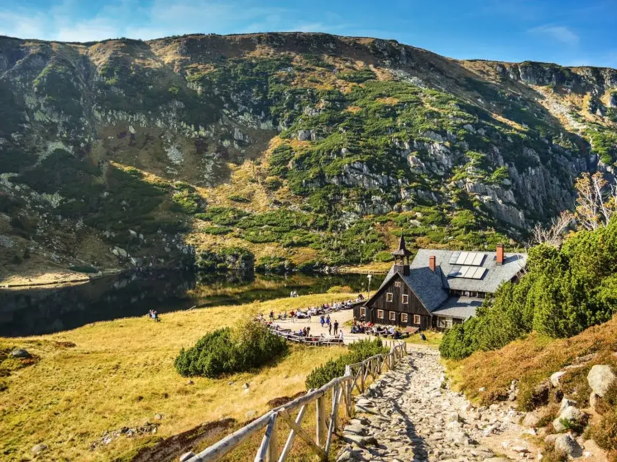 Kamienna ścieżka prowadzi do schroniska w polskich g&oacute;rach, gdzie nad jeziorem rozciąga się malowniczy krajobraz.