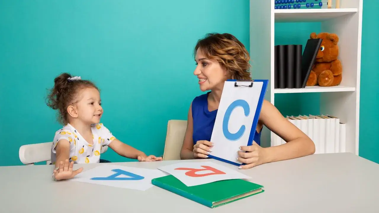 Nauczycielka pokazuje dziecku literę 