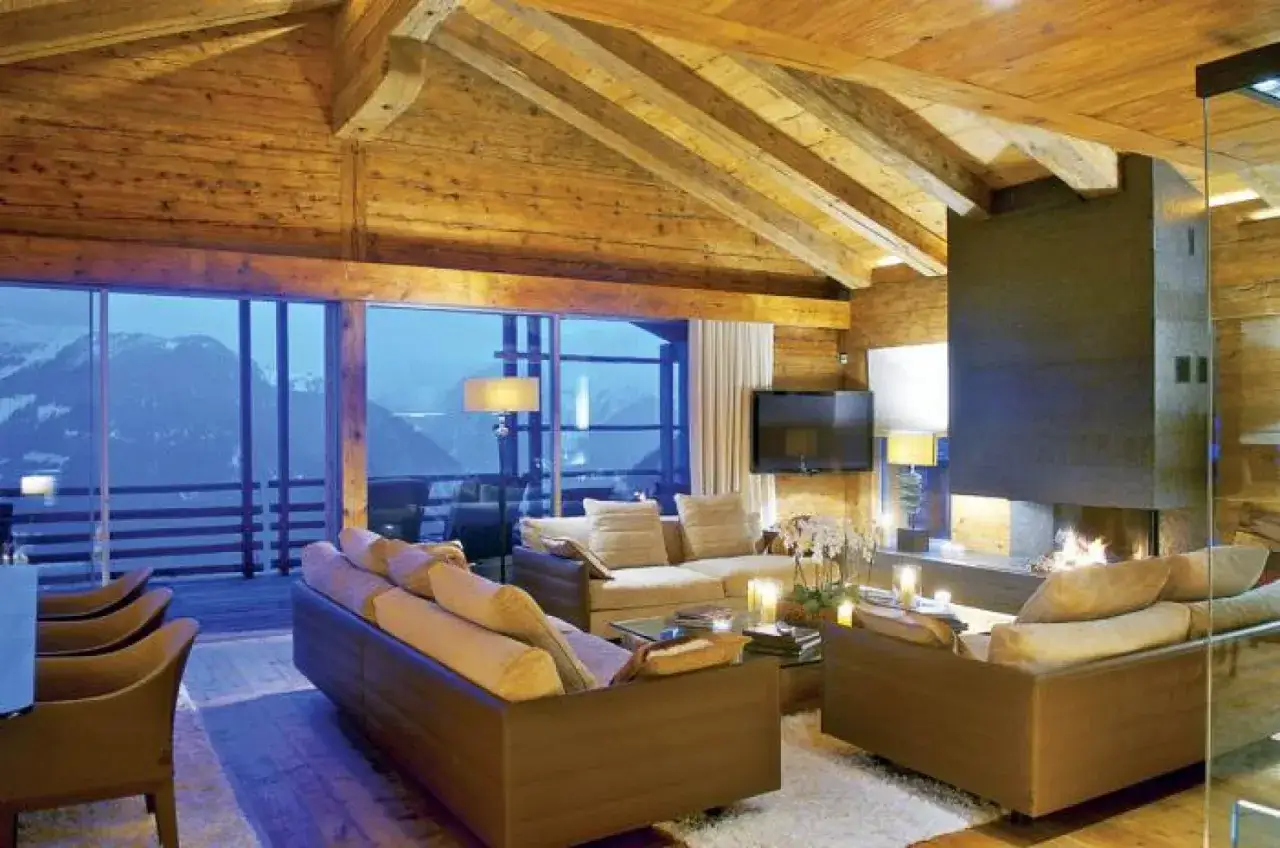 Przytulny salon w nowoczesnych domach z drewna i szkła. Kominek, wygodne sofy i widok na g&oacute;ry.