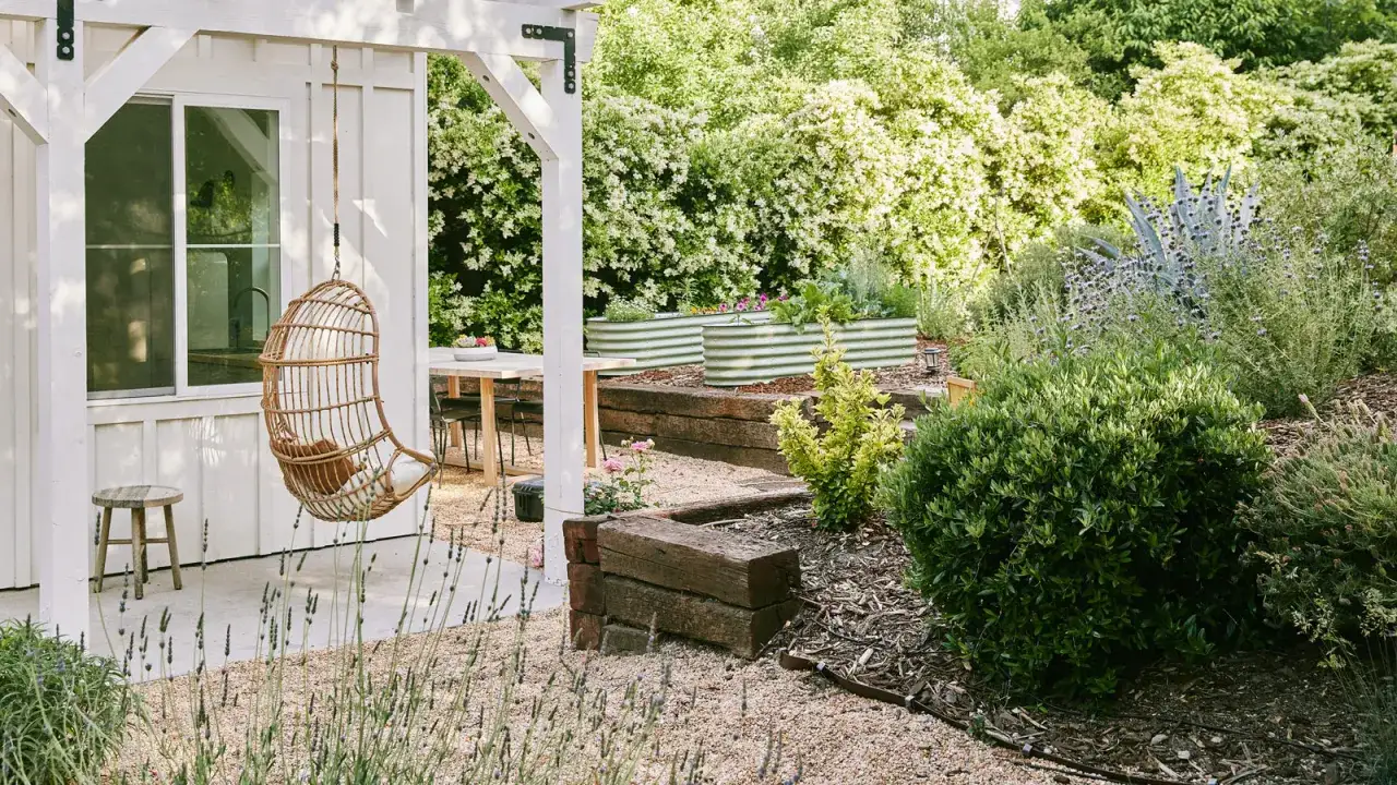 Relaks w ogrodzie: huśtawka z wikliny, drewniane obrzeża rabat i stoły. Inspiracje ogrodowe z drewna.