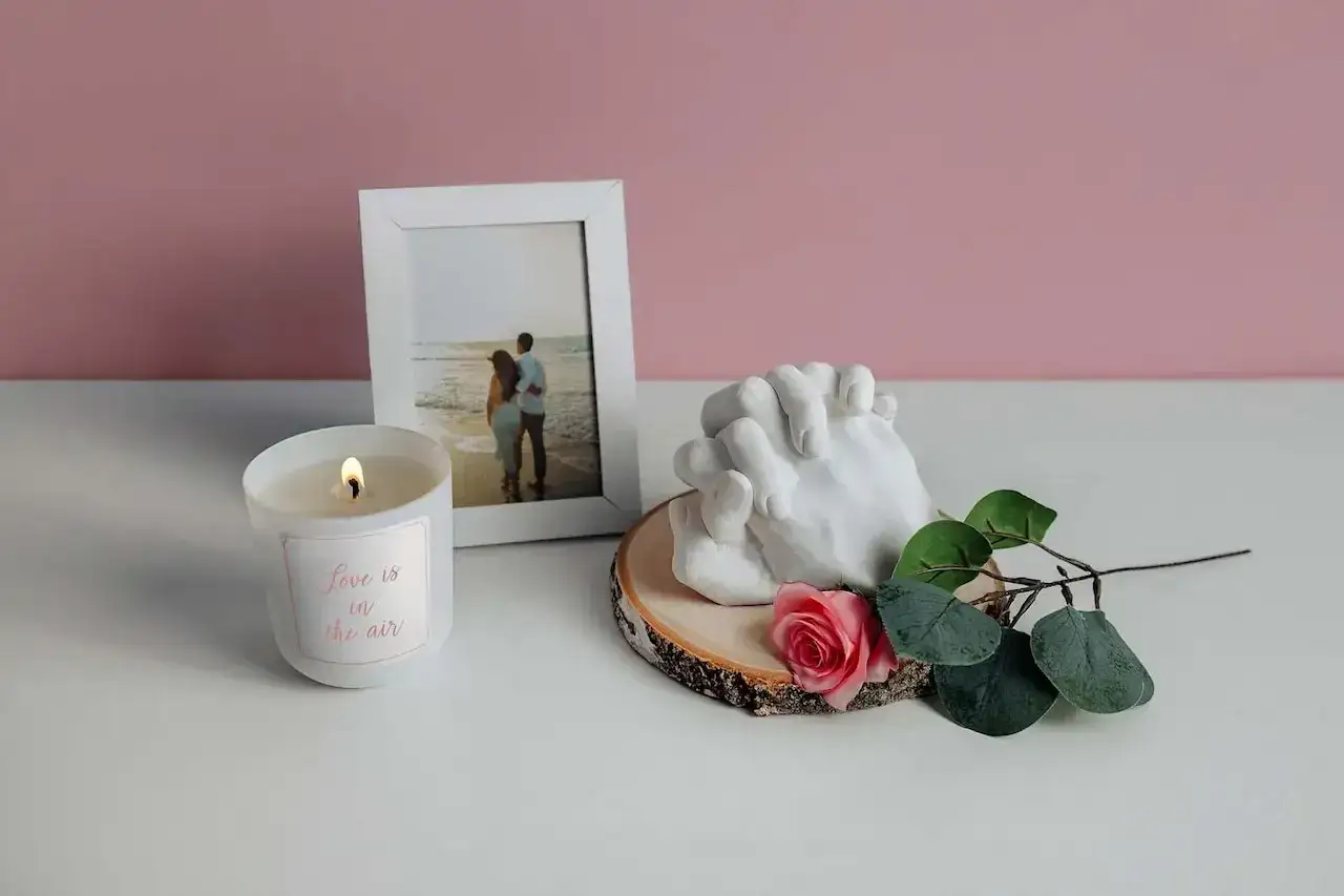 Gips ceramiczny w formie splecionych dłoni, obok ramki ze zdjęciem pary i świecy. Idealny pomysł, jak rozrobić gips ceramiczny na pamiątkę.