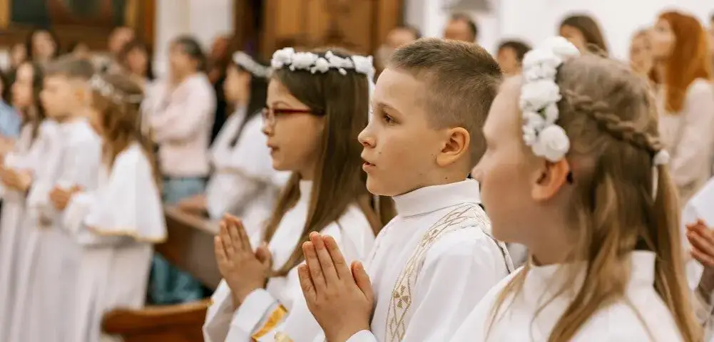 dziecko z chrzestnymi w kościele komunia