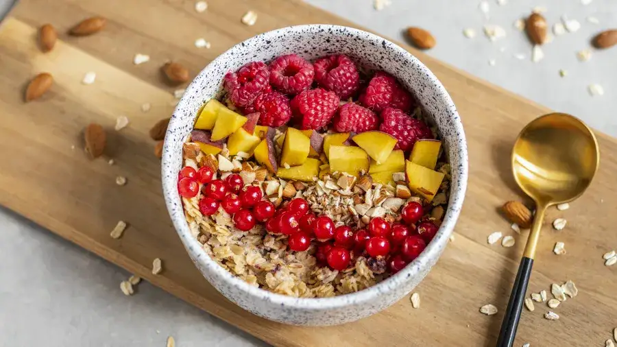 Miska owsianki z owocami i nasionami, z rozmytym tłem przedstawiającym zdrowe jelita lub schemat trawienia