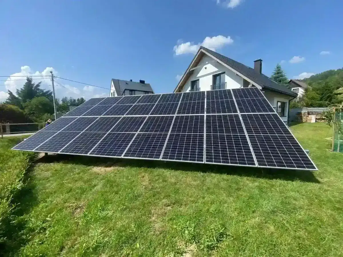 Panele bifacial na trawniku przed domem. Choć wydajne, ich montaż i konserwacja mogą stanowić wyzwanie, co jest jednym z ich wad.