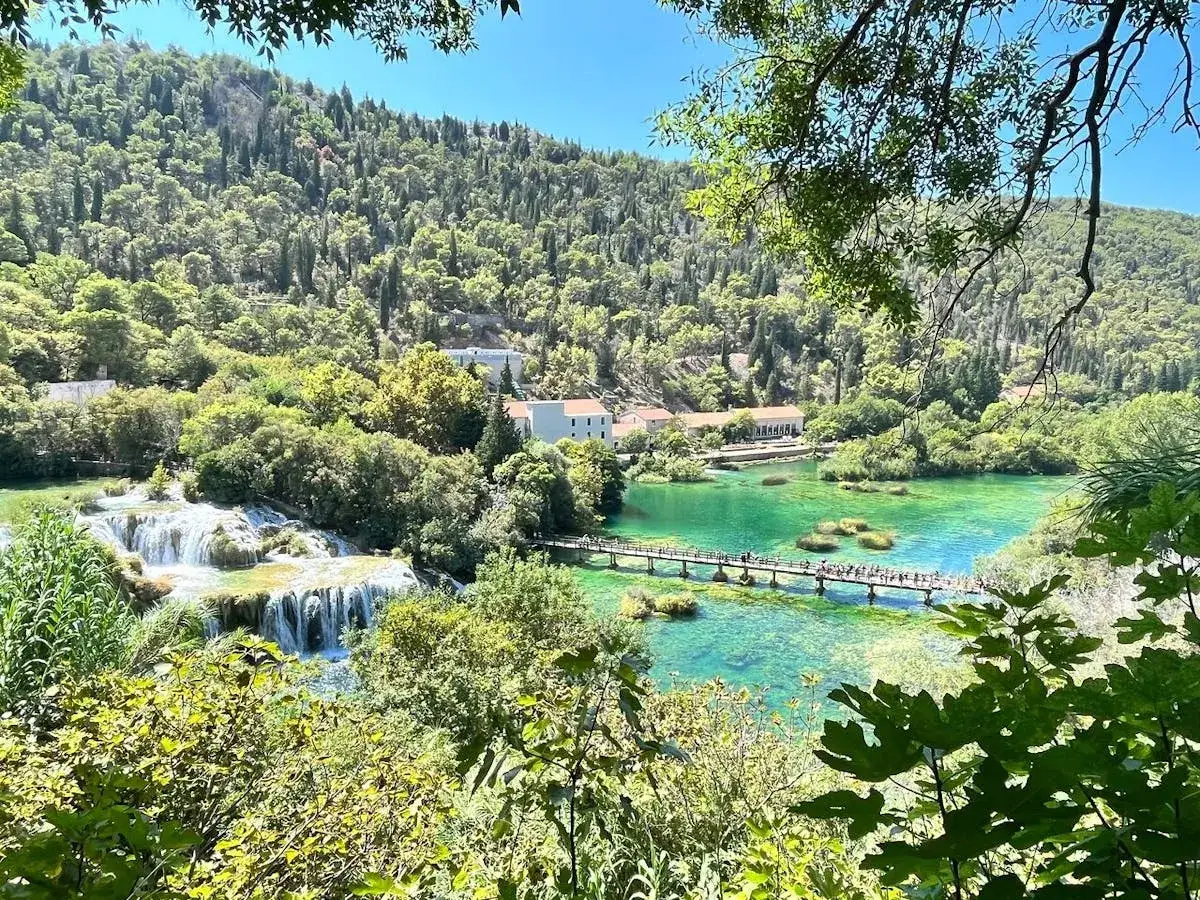 Malownicze wodospady i turkusowa woda w Parku Narodowym Krka, niedaleko Szybenika w Chorwacji. Drewniany mostek dla turystów.