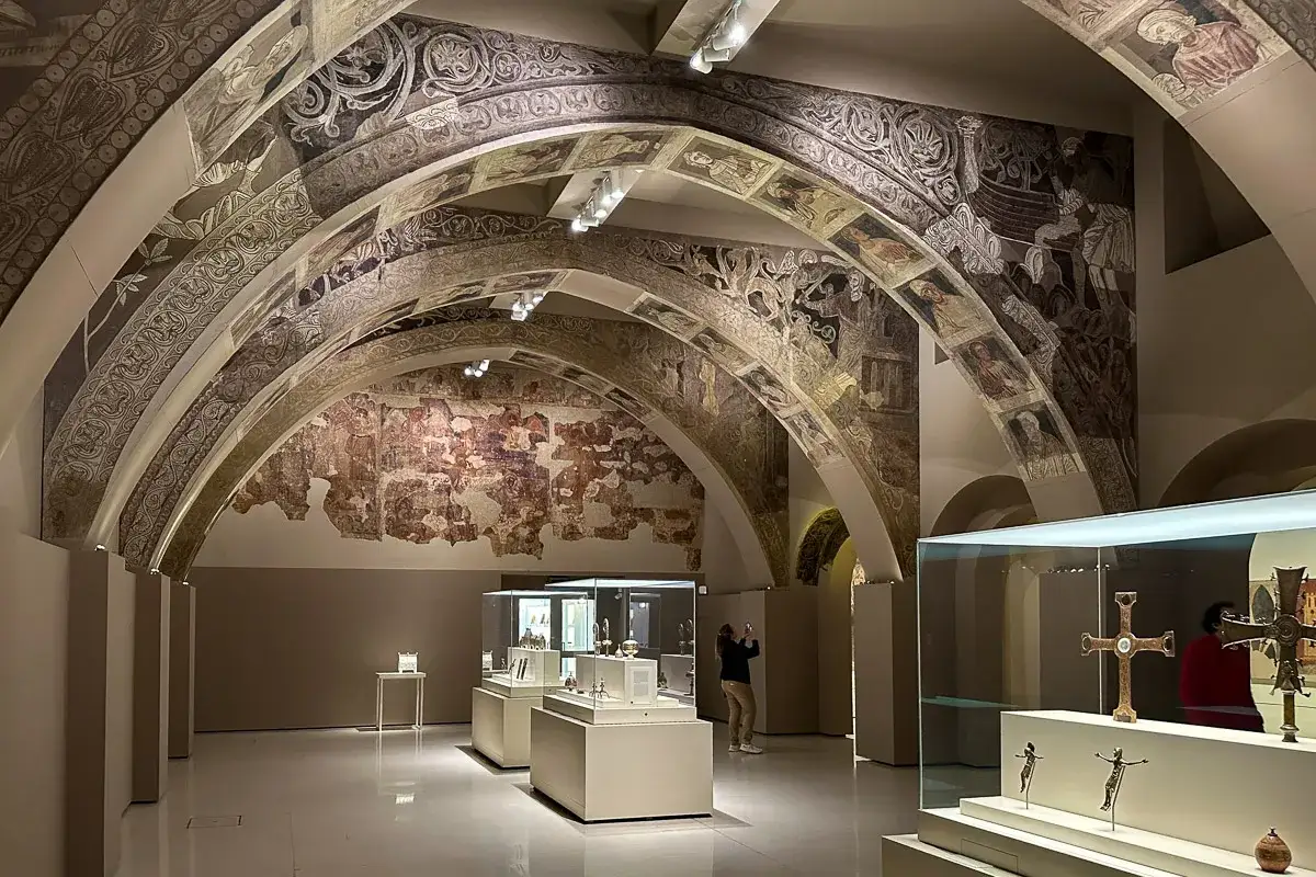 Wnętrze muzeum sztuki w Barcelonie z malowanymi sklepieniami i eksponatami.