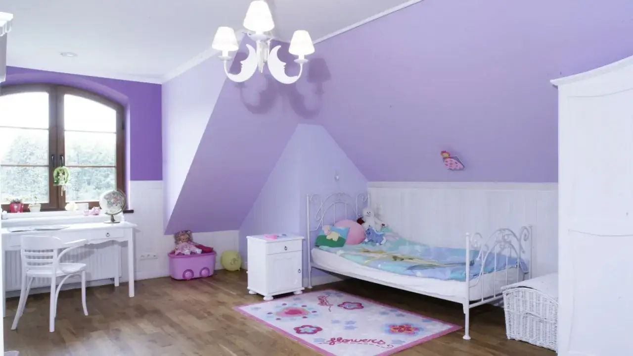 Nowoczesny pokój dla dziewczynki na poddaszu. W fioletowych ścianach, białe meble i łóżko z bajkową pościelą.