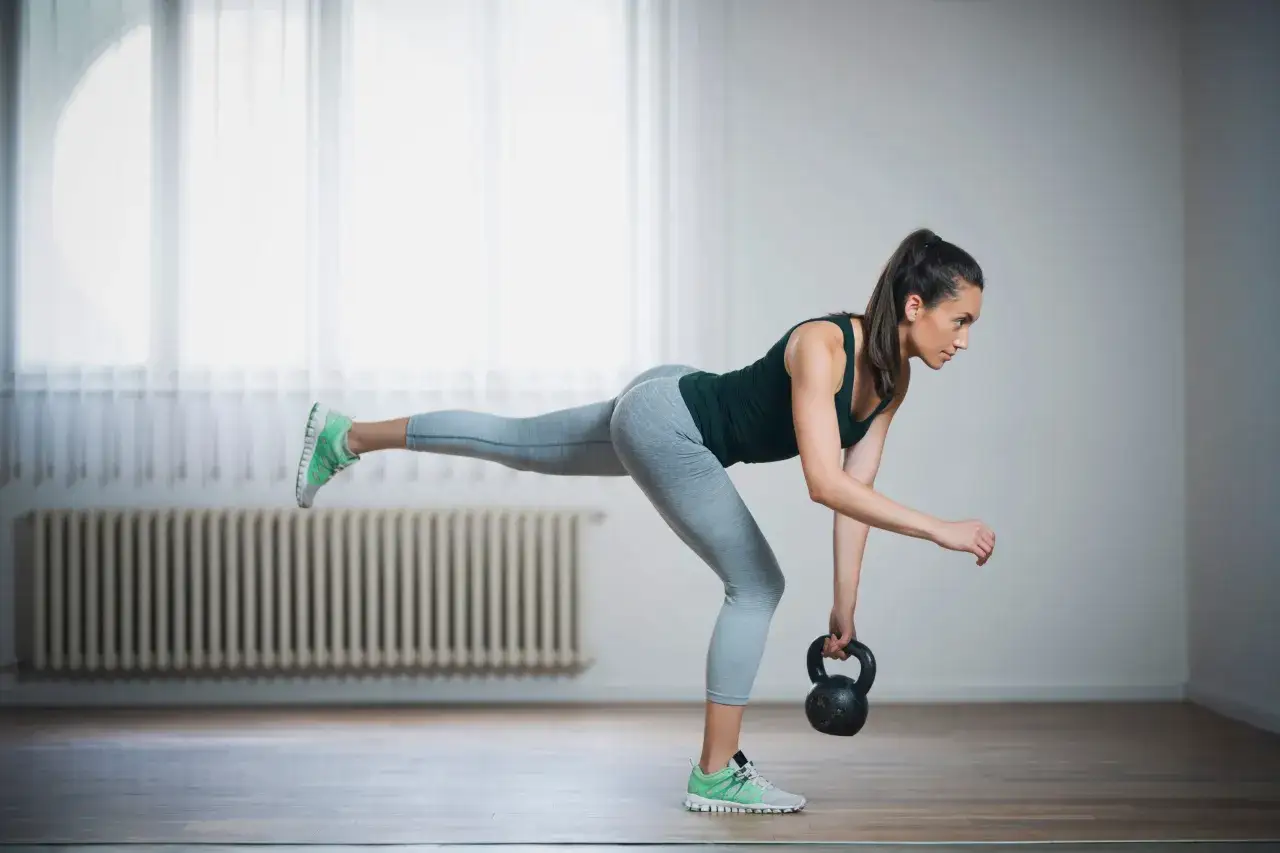 Kobieta wykonuje ćwiczenie z kettlebell, które pomaga jak pozbyć się cellulitu z ud.
