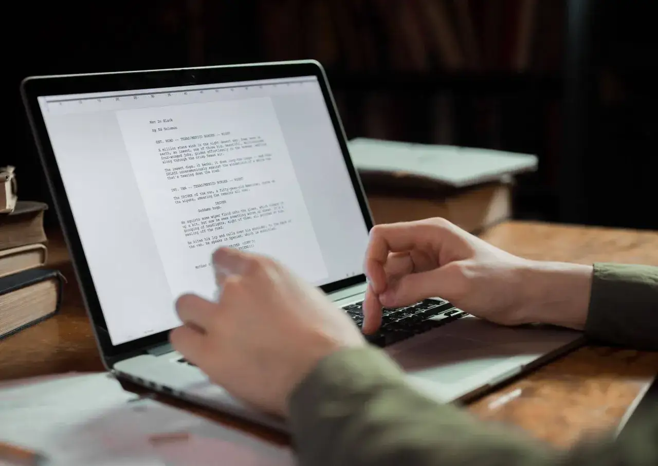 wydrukowany scenariusz filmowy leżący na stole obok laptopa