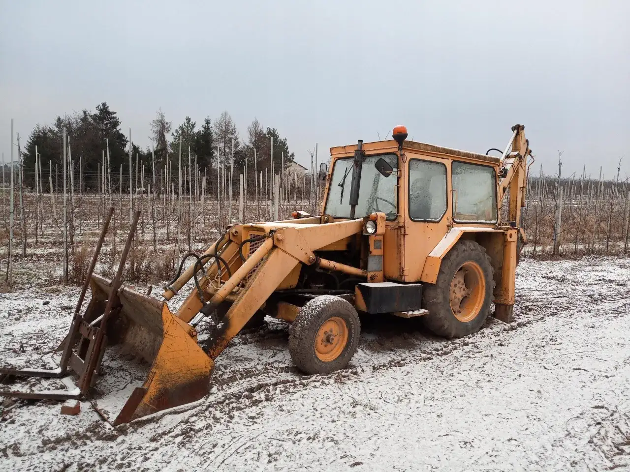 Żółta koparka Ostrówek stoi na zaśnieżonym polu. Zastanawiasz się, ile waży koparka Ostrówek?