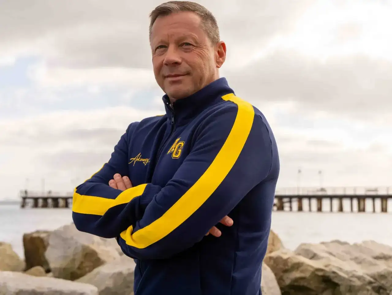 Mężczyzna w bluzie Arki Gdynia, z rękami skrzyżowanymi na piersi. Czy to zapowiedź nowych pogłoski transferowe?