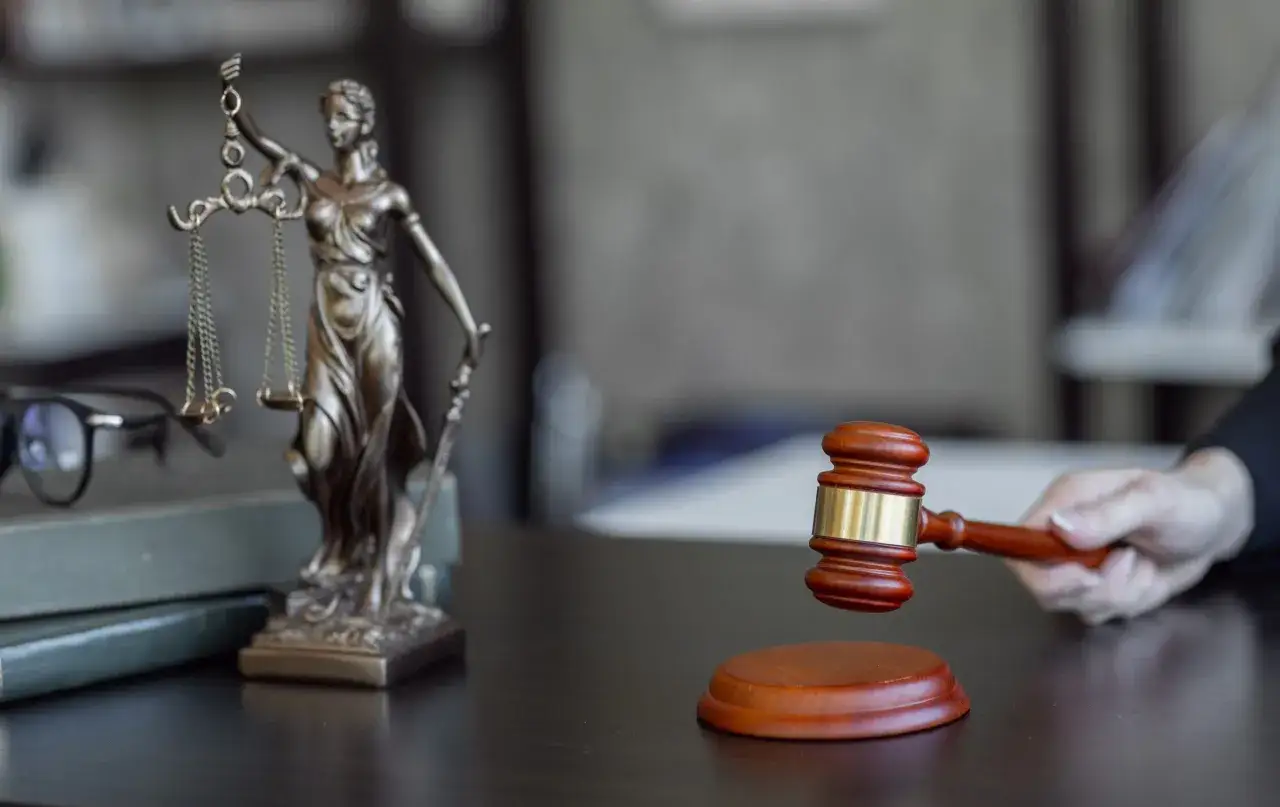 Na biurku prawnika, obok Temidy i okularów, młotek sędziowski czeka na moment ogłoszenia wyroku. Ile czasu idzie pozew do pozwanego?