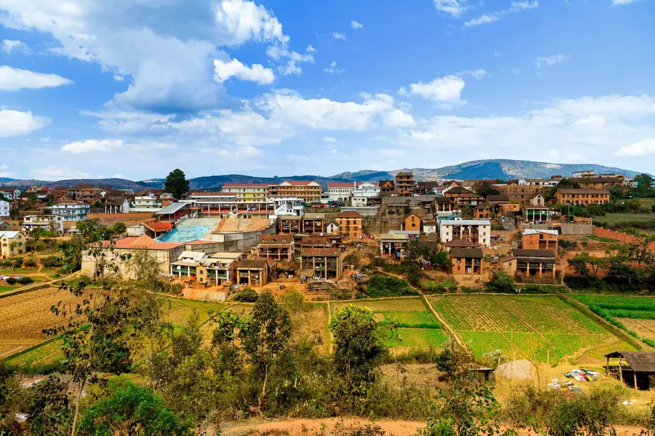 Widok na miasteczko na Madagaskarze, z polami uprawnymi i wzg&oacute;rzami w tle. Idealne miejsce na wycieczkę na Madagaskar.