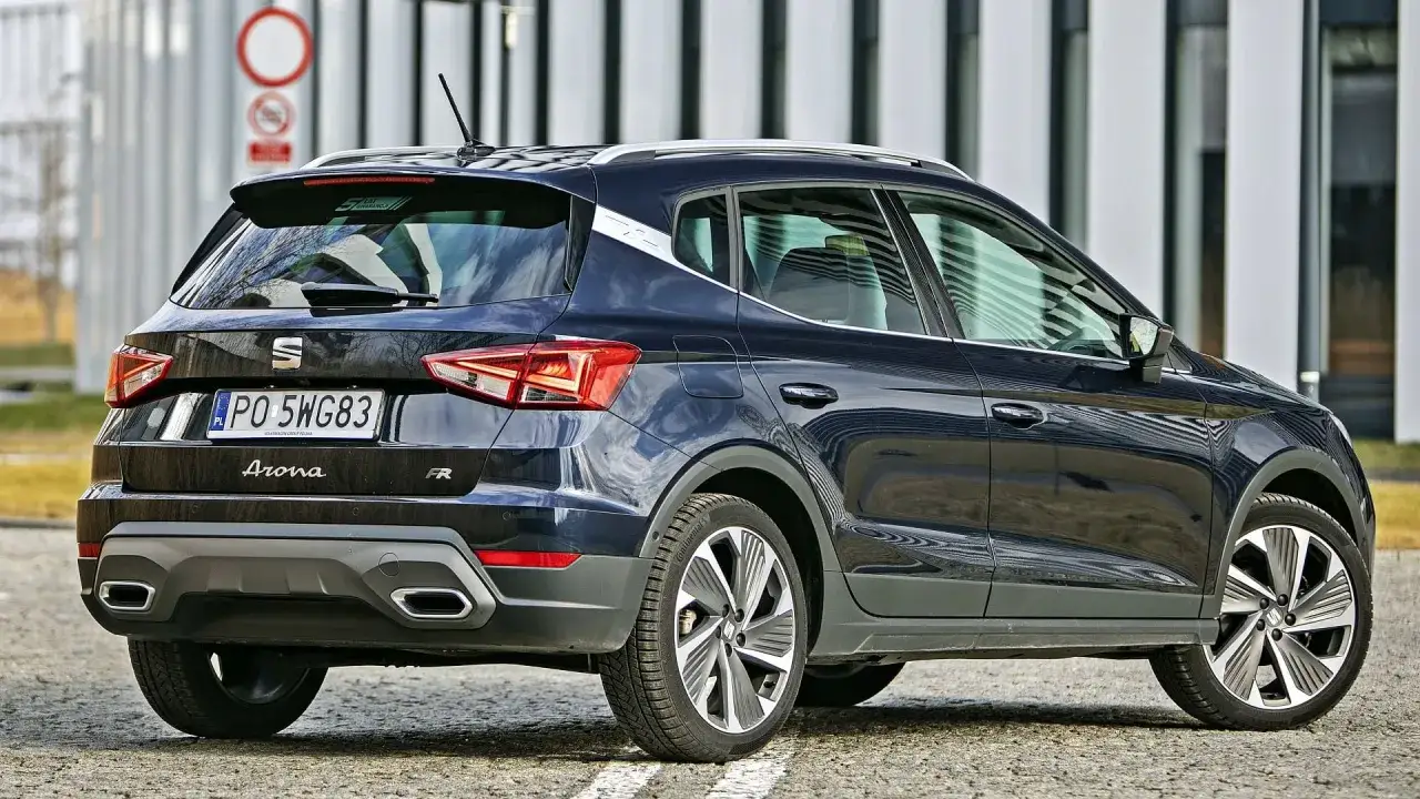 Ciemnogranatowy Seat Arona FR z widocznymi wymiarami, zaparkowany na tle nowoczesnego budynku.