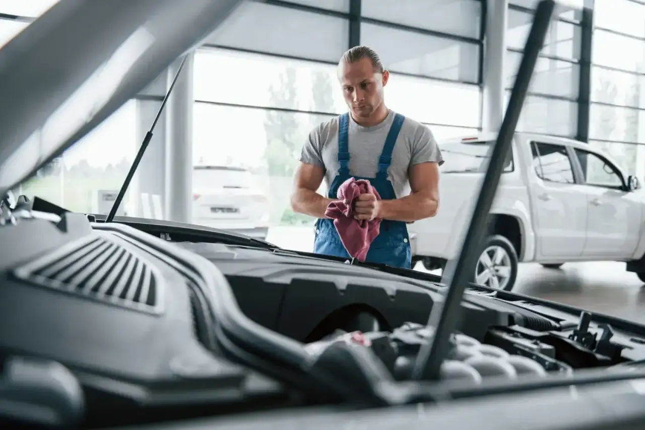 Mechanik z ręcznikiem przy otwartej masce samochodu. Rozważasz naprawa samochodu w leasingu a koszty?