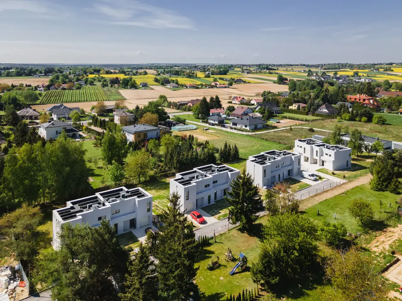 Nowe domy od dewelopera. Czy kupując dom od dewelopera płacę podatek? Nowoczesna architektura, pola i zielone krajobrazy.