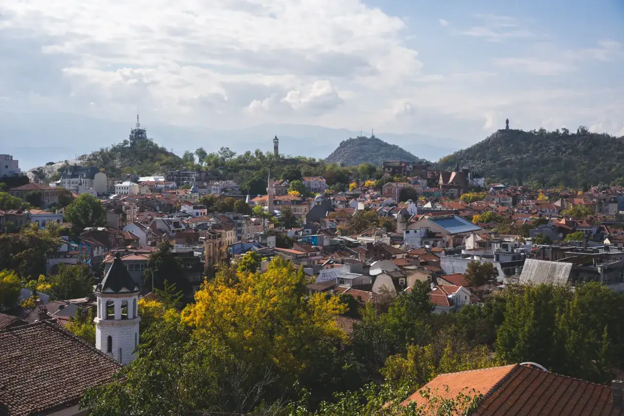 Widok na Plovdiv w Bułgarii z charakterystycznymi wzgórzami i dachami. W oddali widać wieżę telewizyjną.