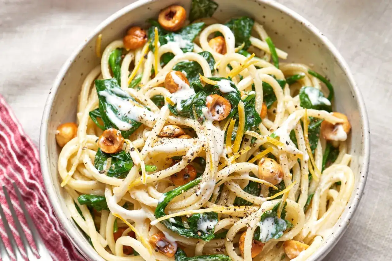Szybki makaron z sosem bez mięsa, ze szpinakiem, orzechami laskowymi i sk&oacute;rką cytrynową.