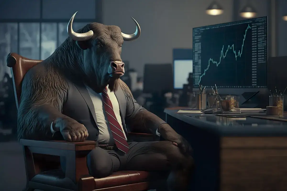 Byk w garniturze siedzi przy biurku, patrząc na wykres giełdowy. Czy to symbolizuje, co to jest bessa, gdy ceny spadają?