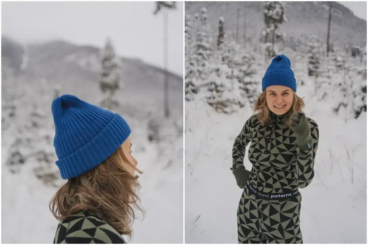 Uśmiechnięta dziewczyna w niebieskiej czapce z merynosa i wzorzystym stroju cieszy się zimowym krajobrazem.
