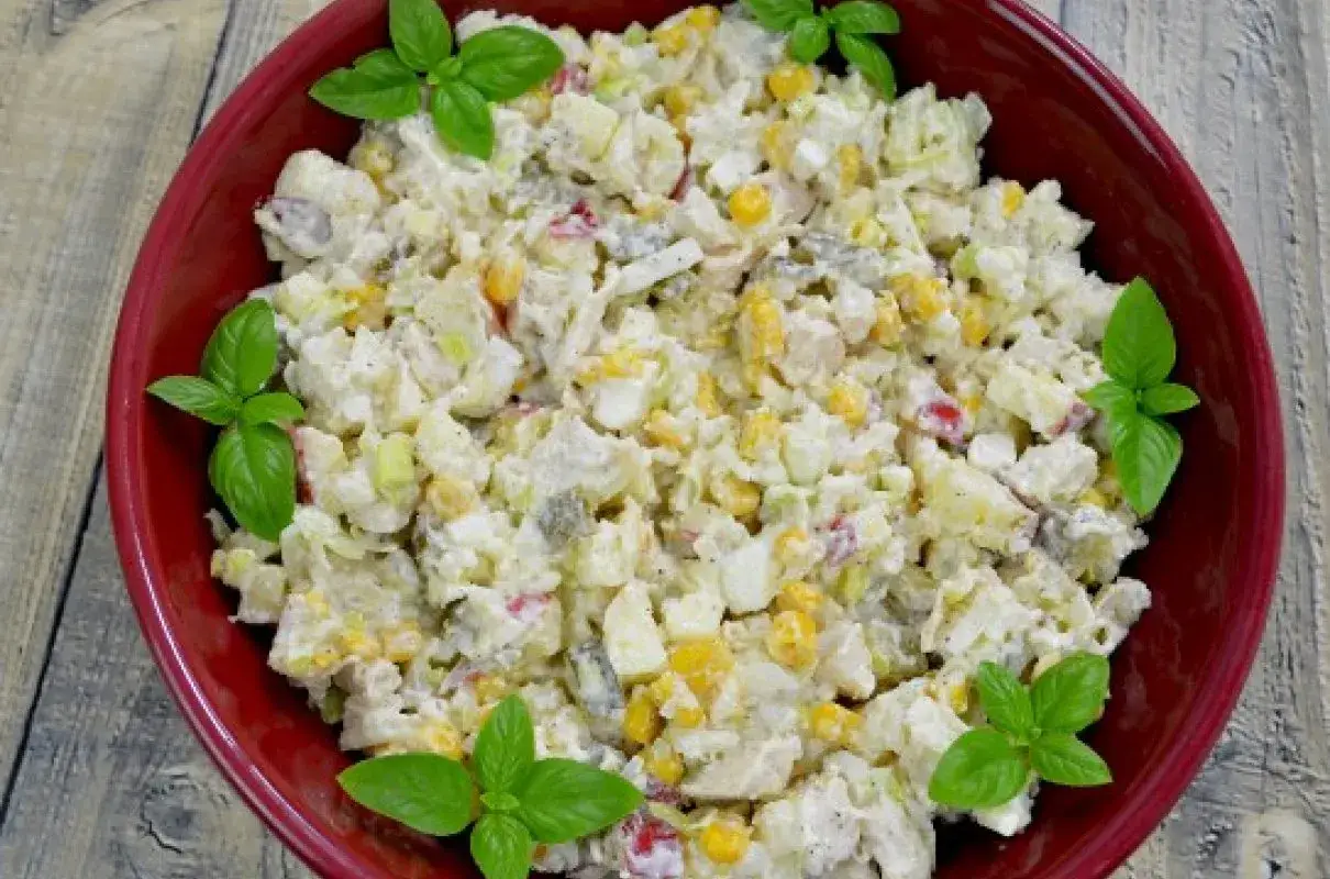 Pyszna pasta z gotowanego kurczaka z kukurydzą, jajkiem i warzywami, udekorowana listkami bazylii.