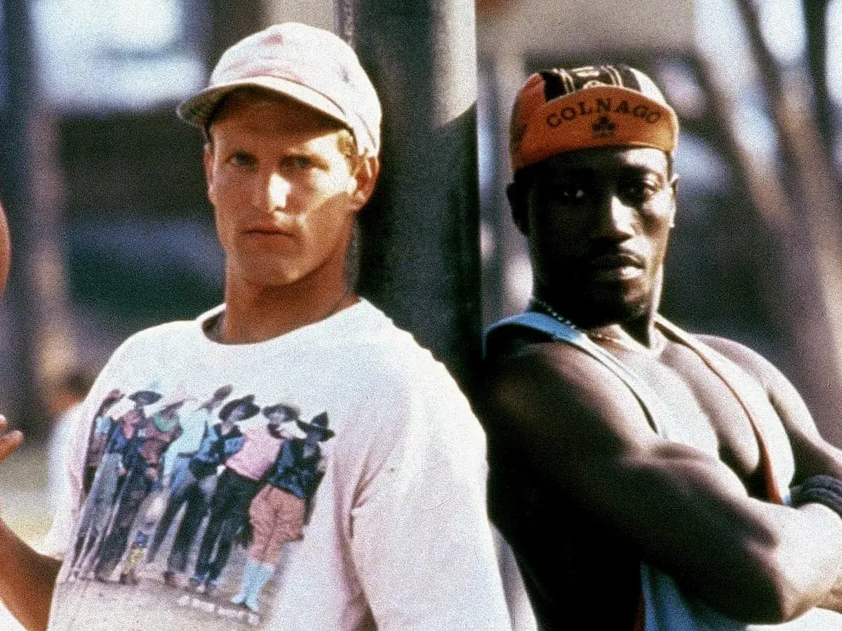 Dwóch mężczyzn, jeden w czapce z daszkiem, drugi w pomarańczowej czapeczce z napisem 