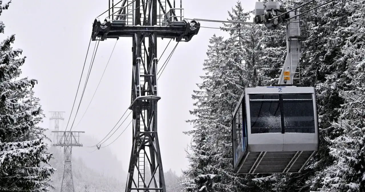 Kolejka na Kasprowy Wierch w zimowej scenerii. Śnieg pokrywa drzewa i konstrukcję wyciągu, tworząc malowniczy widok.