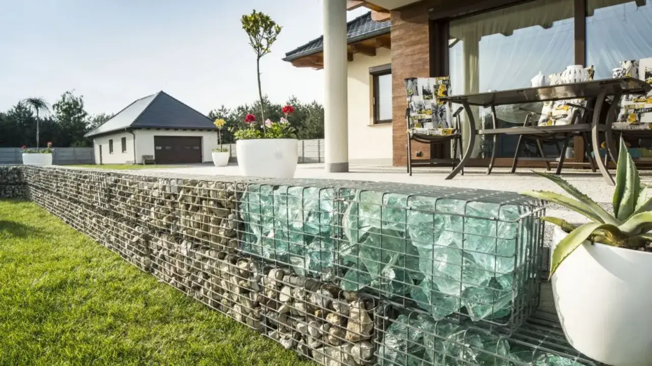 Nowoczesne gabiony w ogrodzie aranżacje: kamień i szkło tworzą unikalną ozdobę przy tarasie z meblami i domem.