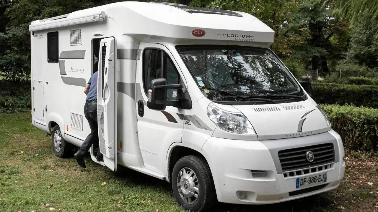 Biały kamper na kat b, z otwieranymi drzwiami, w kt&oacute;rym widać wchodzącą osobę.