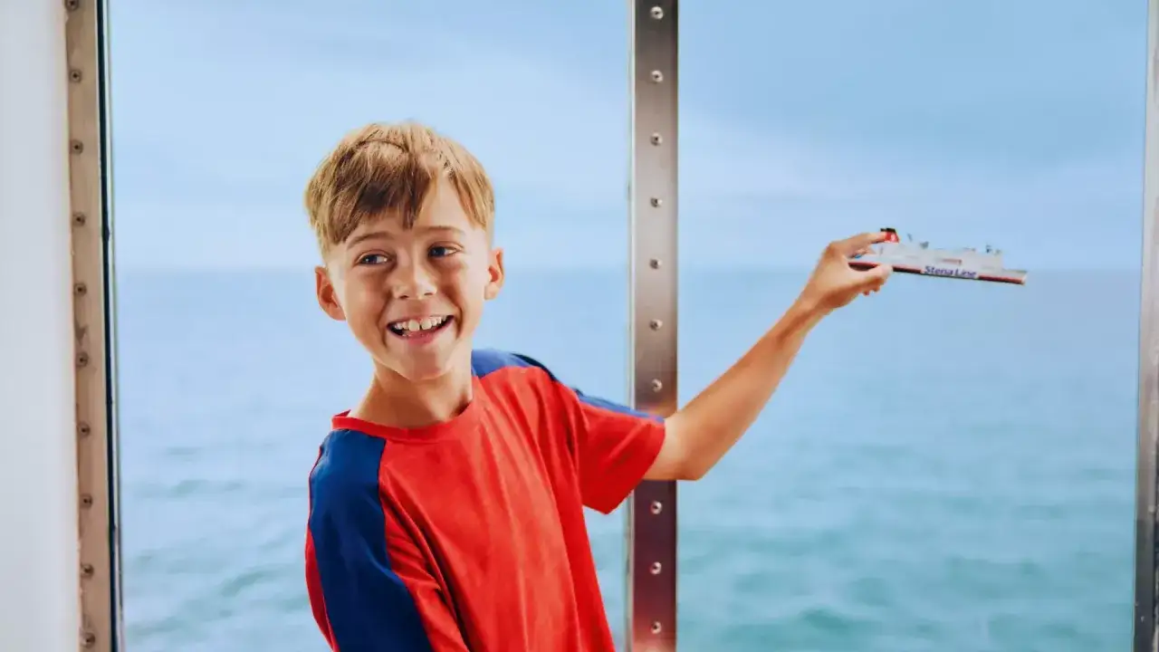 Uśmiechnięty chłopiec trzymający model statku Stena Line, cieszący się atrakcjami na promie.