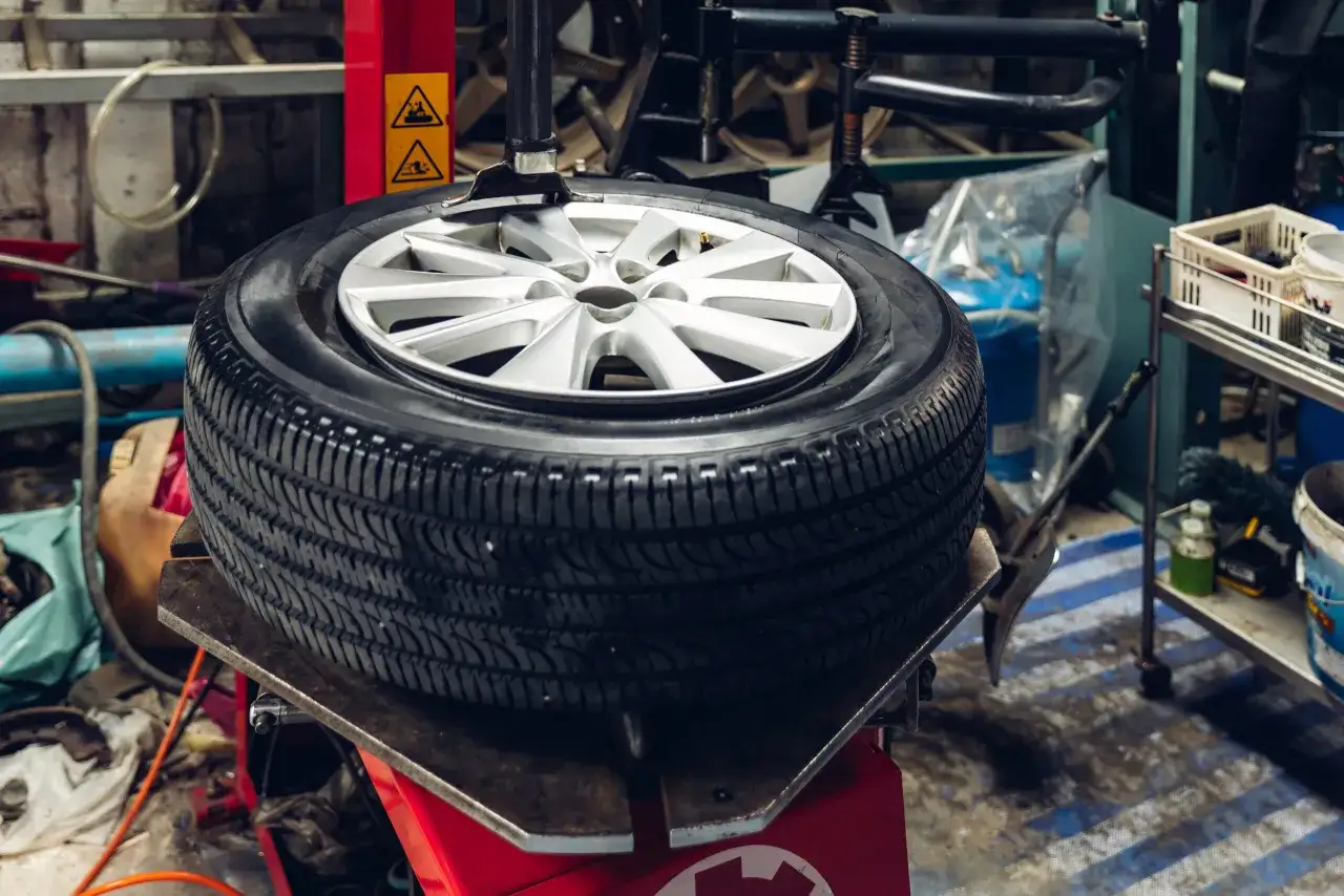 Wulkanizacja: ile kosztuje wymiana opon z wyważeniem? Nowa opona na feldze na maszynie w warsztacie.