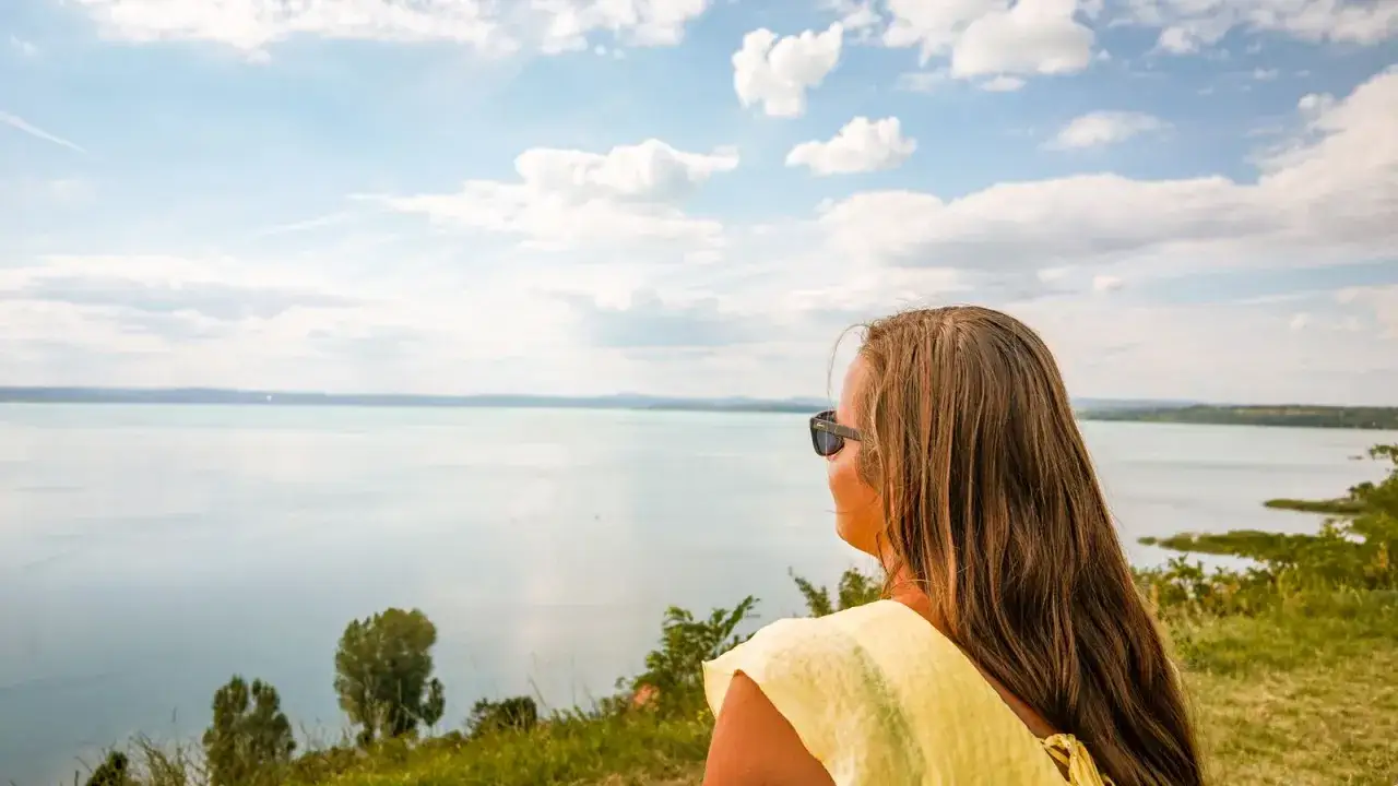 Kobieta w ż&oacute;łtej bluzce podziwia rozległy Balaton na Węgrzech.