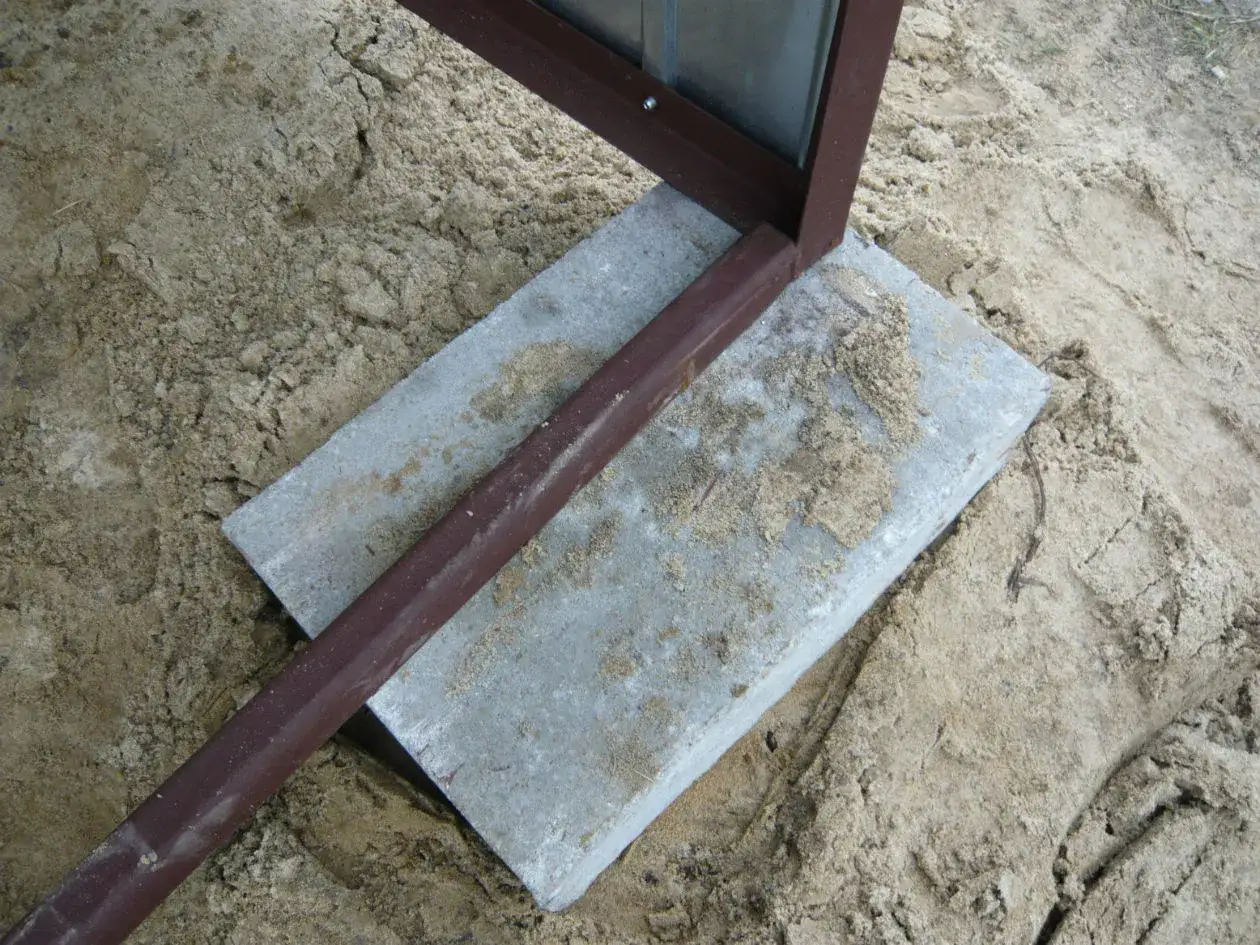 Fragment konstrukcji garażu blasznego oparty na płycie betonowej, przygotowany do montażu. Pokazuje, jak zakotwić garaż blaszany do kostki brukowej.