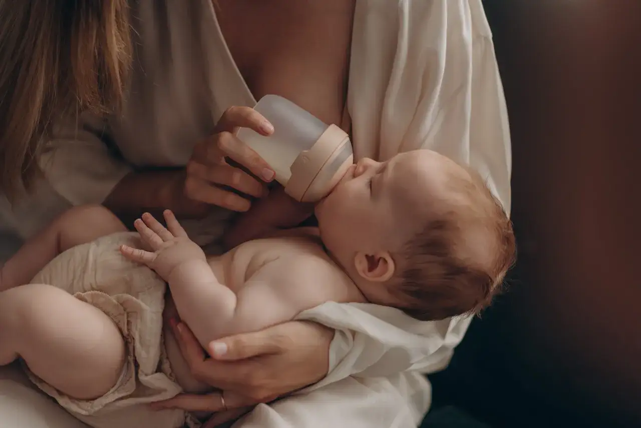 Delikatne karmienie noworodka butelką, pokazujące bliskość i troskę.
