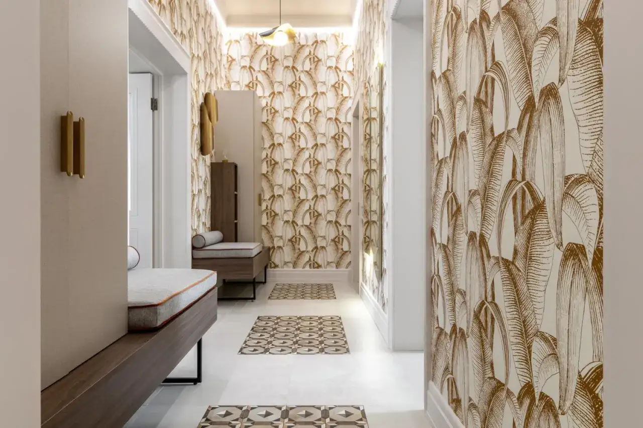Elegancki przedpok&oacute;j z tapetą w liście bananowca. Długie ławki, ozdobne płytki na podłodze i złote akcenty tworzą przytulną atmosferę.