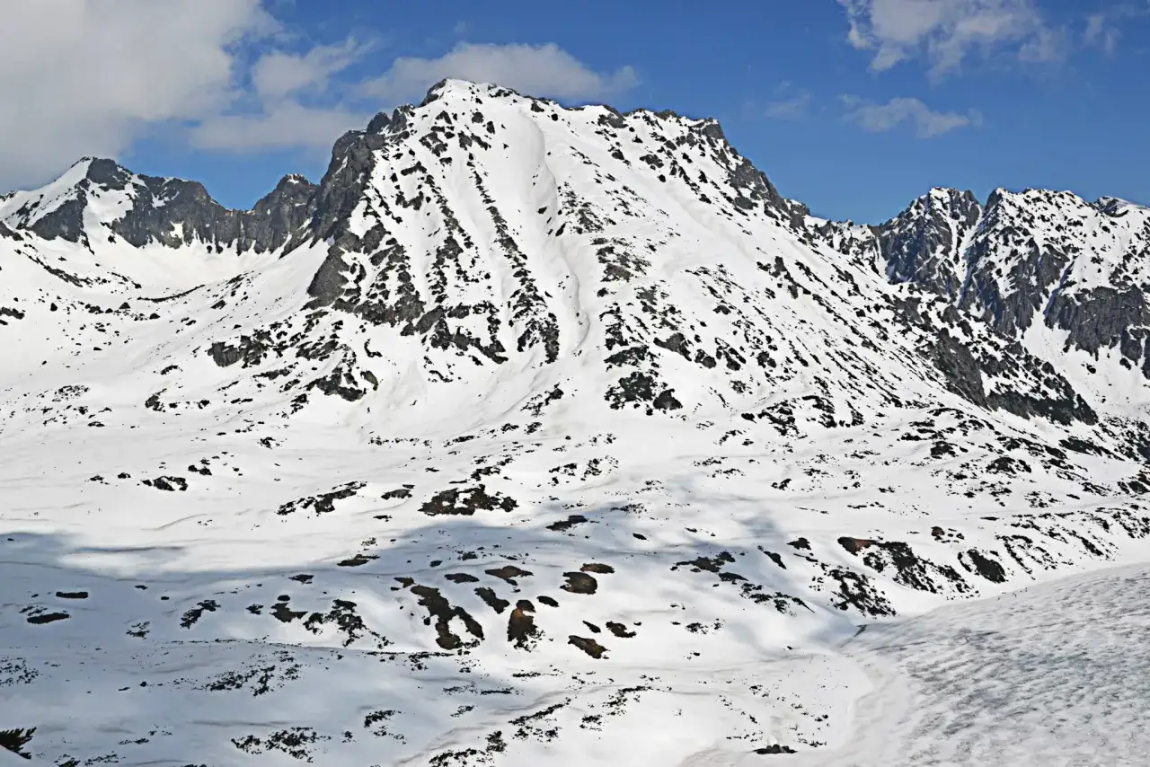 Zimowy krajobraz Tatr z ośnieżonym Kozi Wierch. Widać skaliste zbocza i ślady szlaków.