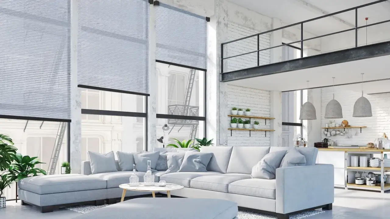 Nowoczesna dekoracja okien w lofcie. Jasne rolety podkreślają przestronność salonu z widokiem na miejską architekturę.