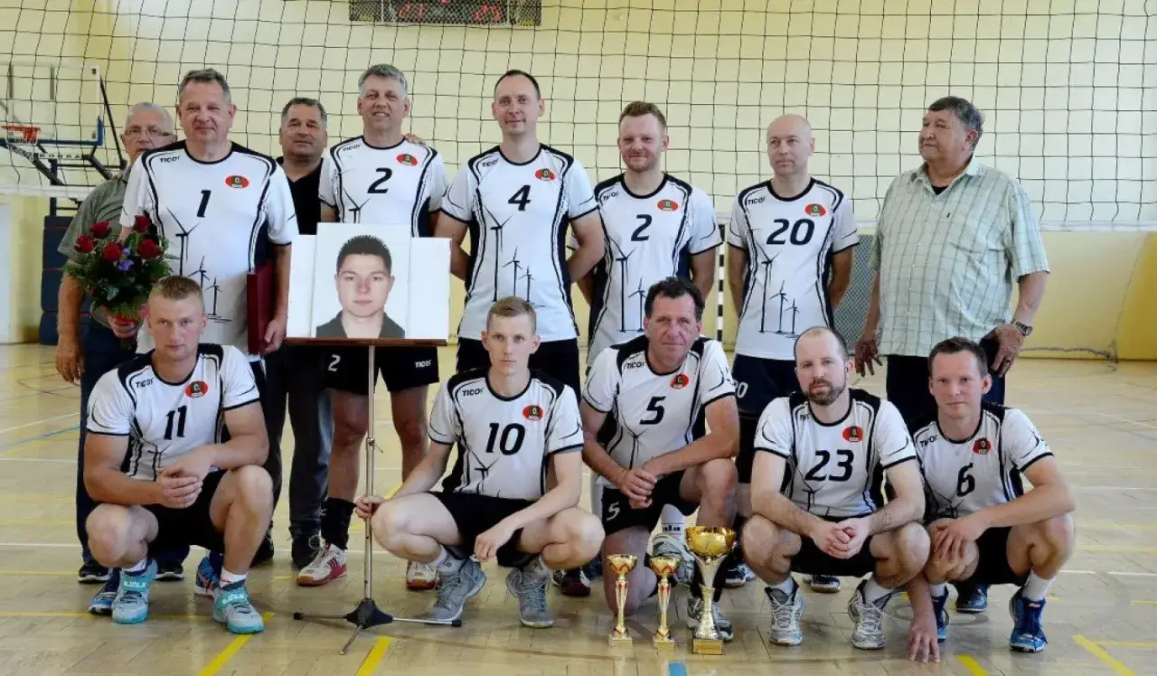 grupa dorosłych grająca w siatk&oacute;wkę na hali sportowej