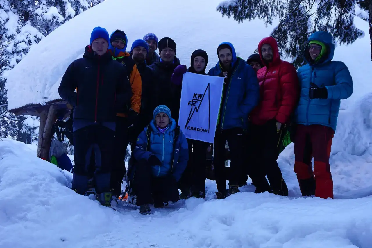 Grupa ludzi w zimowych kurtkach i czapkach, gotowa na wyprawę. Widać, jak się ubrać w g&oacute;ry zimą: warstwowo i ciepło.