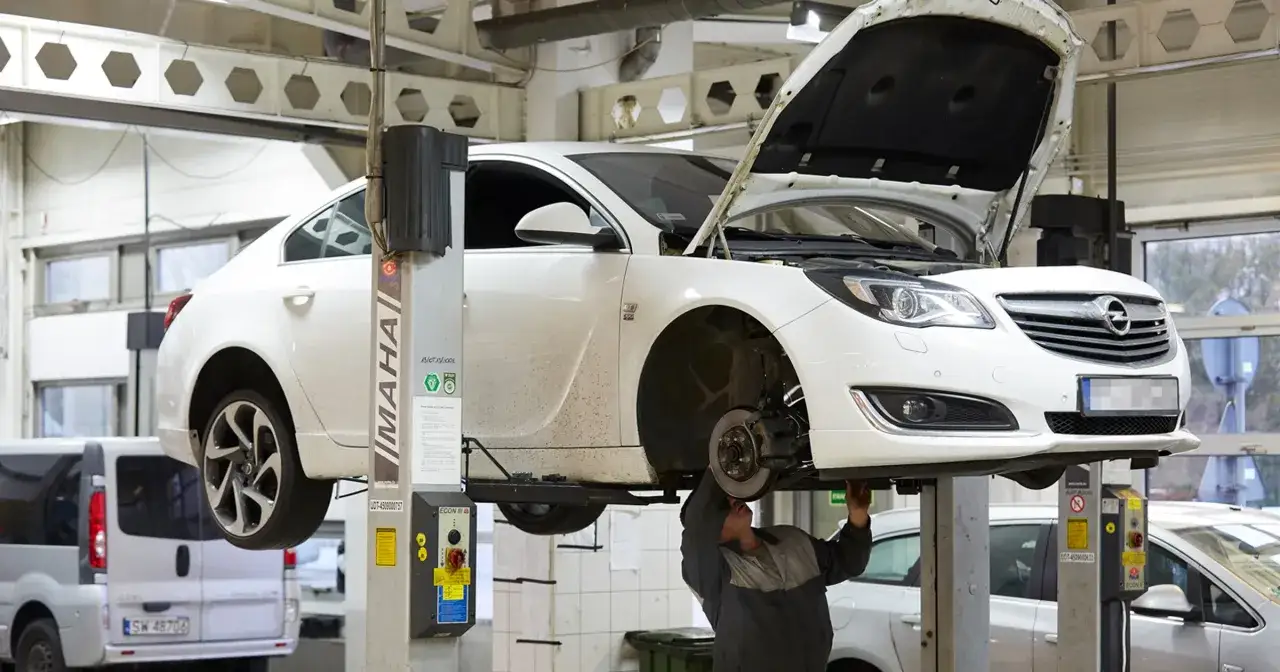 Ręka trzymająca lupę nad dokumentem z kosztorysem naprawy samochodu