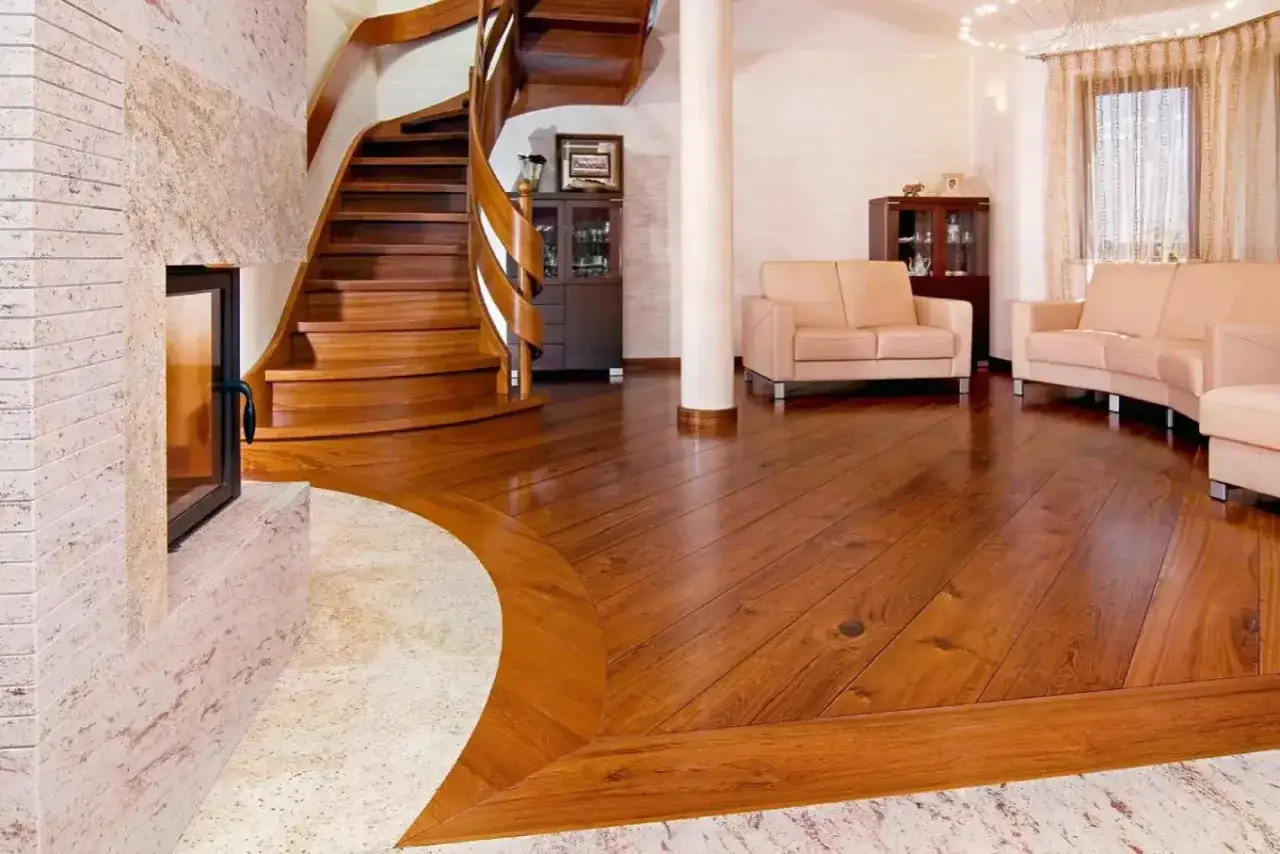 Eleganckie łączenie podłogi drewnianej z płytkami przy kominku i schodach. Wnętrze z sofami i meblami.