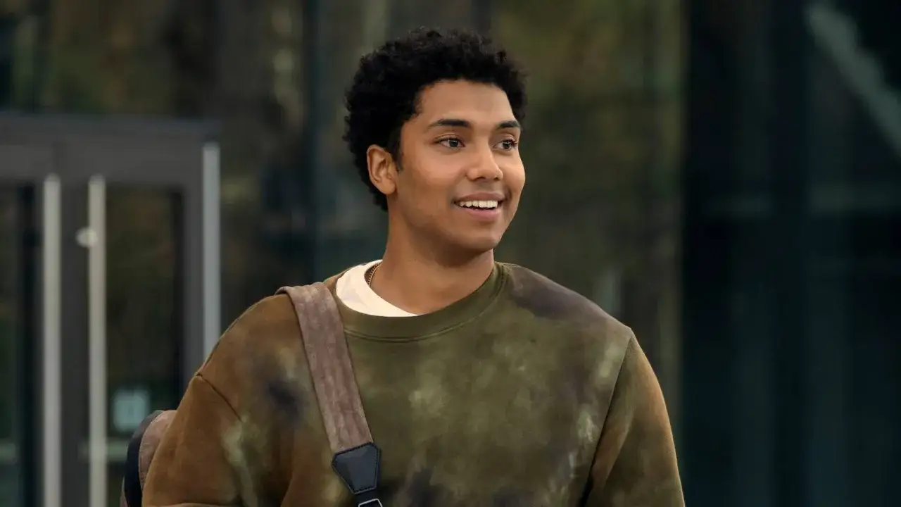 Uśmiechnięty młody mężczyzna z kręconymi włosami, w bluzie z tie-dye, jakby przygotowywał się do kolejnych film&oacute;w, seriali i program&oacute;w z udziałem Chance Perdomo.