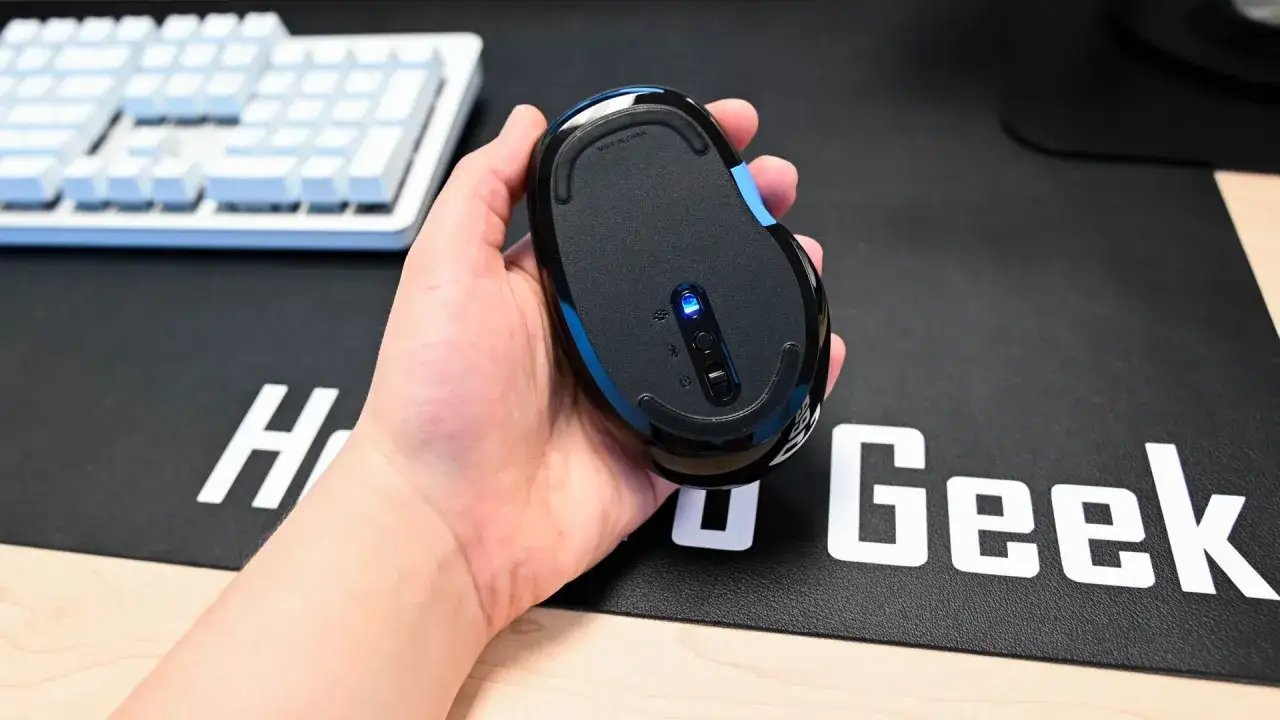 Dłoń trzyma myszkę bezprzewodową z niebieską diodą. Dowiedz się, jak podłączyć myszkę bezprzewodową do laptopa bez USB, korzystając z Bluetooth.