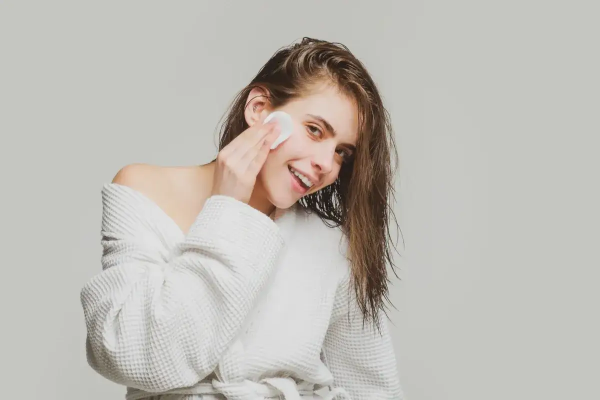 kobieta delikatnie usuwająca farbę ze sk&oacute;ry twarzy