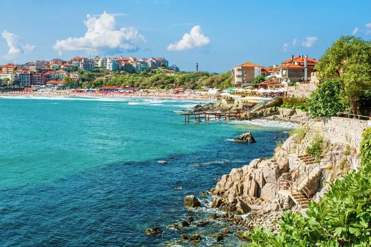 Słoneczna plaża i turkusowe morze, idealne rumunia atrakcje. Widok na miasteczko z czerwonymi dachami i kamieniste wybrzeże ze schodami.