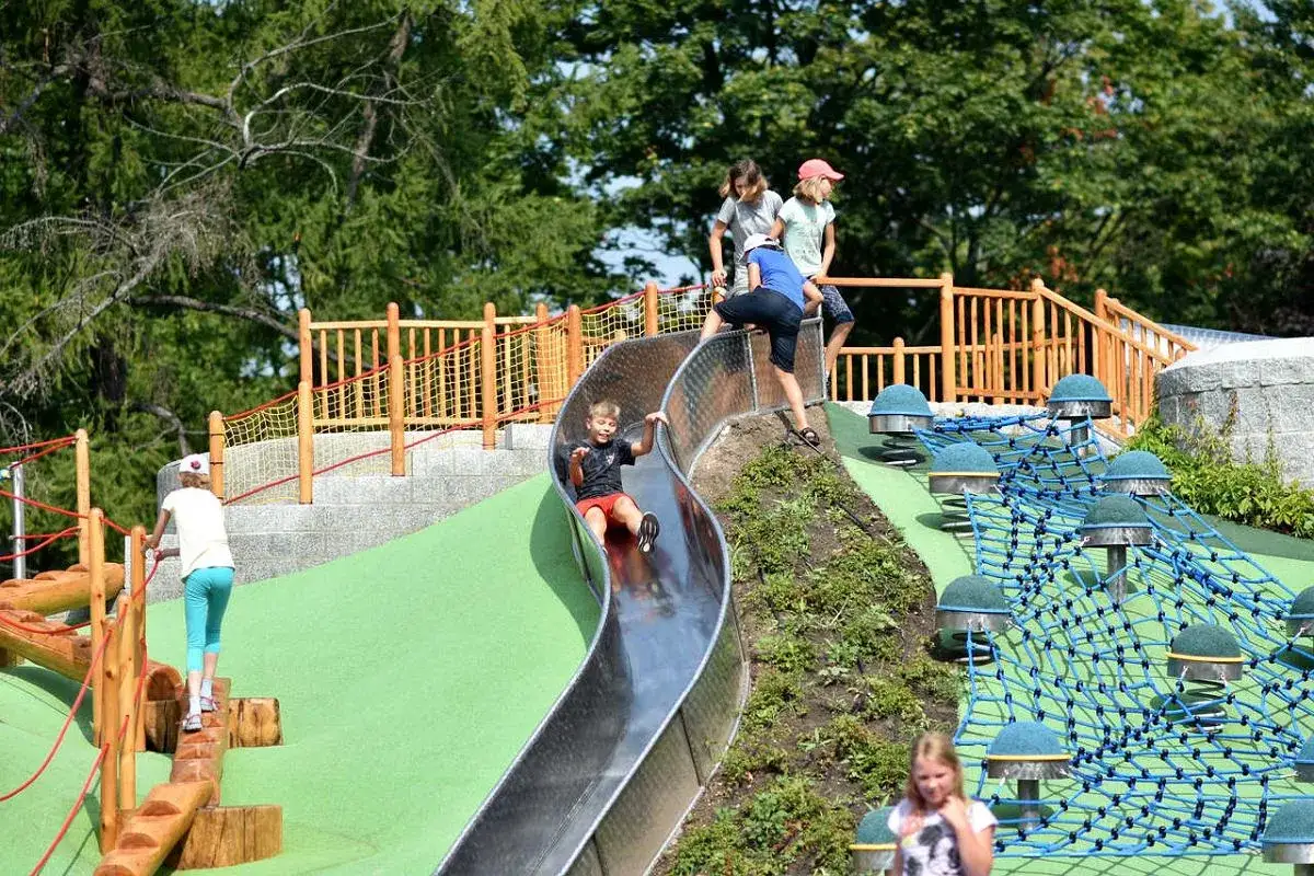 Dzieci bawią się na nowoczesnym placu zabaw w Parku Ujazdowskim. Metalowa zjeżdżalnia i siatki wspinaczkowe zapewniają mnóstwo radości.