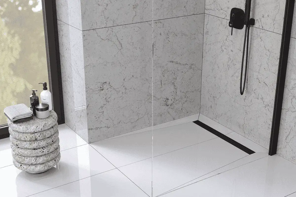 Nowoczesna, mała łazienka z prysznicem walk-in i dyskretnym odpływem liniowym. Marmurowe płytki i czarne detale tworzą elegancką całość.