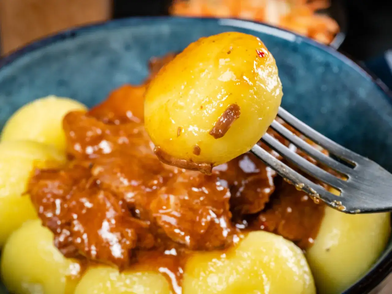 Kluski śląskie z gulaszem na widelcu. Aby kluski śląskie się nie skleiły, warto dodać do nich odrobinę mąki ziemniaczanej.